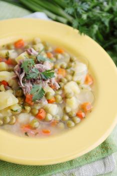 Hot soup with fresh green peas and herbs