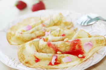 Pancakes with strawberry jam, rose petals and pine nuts