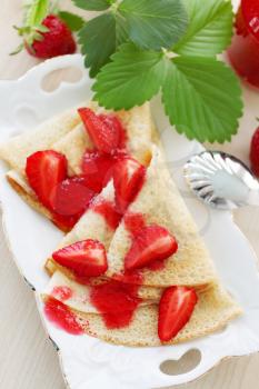 Fried pancakes with fresh strawberries and jam