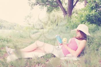Girl in a hat reading a book and eating an apple