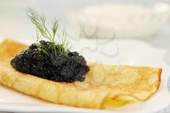 Ruddy pancake with black caviar and dill