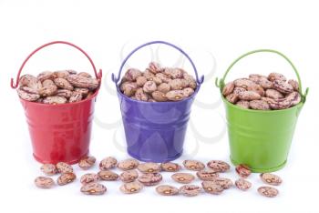 Multicoloured buckets with beans on a white background.
