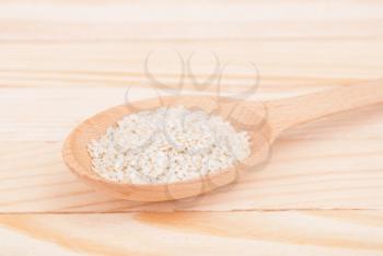 Sesame seeds in a spoon on a wooden table.