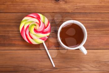 Cup of tea and a lollipop on the wooden table.