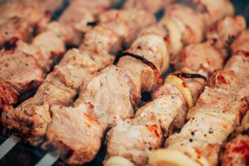 Grilled marinated caucasus barbecue meat shashlik (shish kebab) pork meat grilling on metal skewer, close up