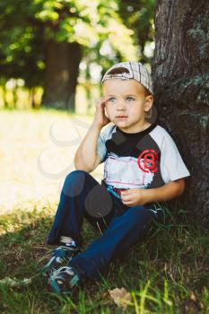 Happy Caucasian Child Boy Sitting Under Tree Outdoor