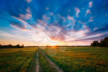 Sunset, Sunrise Over Rural Meadow Field. Bright Dramatic Sky And Country Road Path Way. Countryside Landscape Under Scenic Summer Dramatic Sky In Sunset Dawn Sunrise. Skyline.