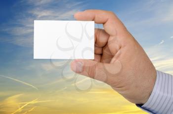 Hand holding a business card on background a beautiful sunset sky