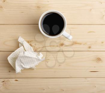 cup of coffee and crumpled paper on wooden table