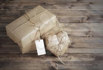 Heart and box wrapped in brown kraft paper with a price tag,  on wooden table closeup
