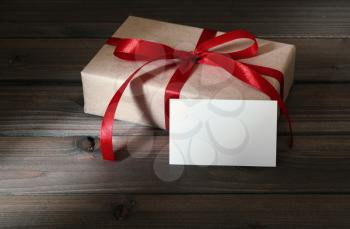 Vintage gift box wrapped in kraft paper and red ribbon on wooden background