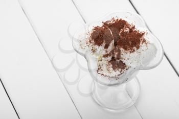 glass of ice cream with chocolate shavings on a white wooden table