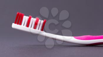 A pink toothbrush on a grey background