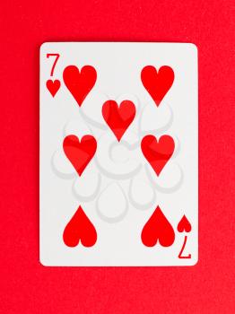 Old playing card (seven) isolated on a red background