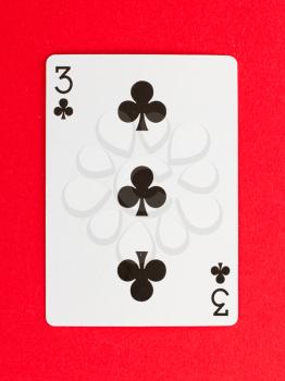 Old playing card (three) isolated on a red background