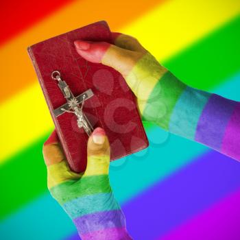 Old hands (woman) holding a very old bible, rainbow flag pattern