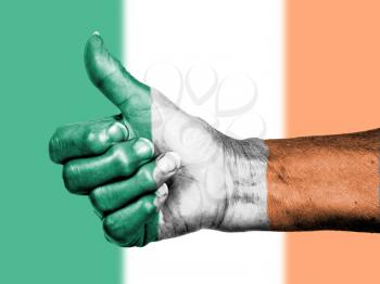 Old woman with arthritis giving the thumbs up sign, wrapped in flag pattern, Ireland