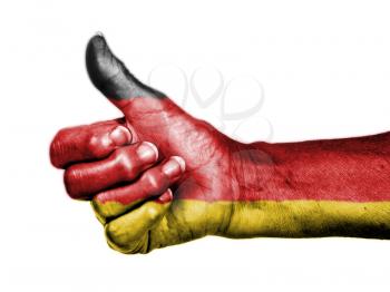 Old woman with arthritis giving the thumbs up sign, wrapped in flag pattern, Germany