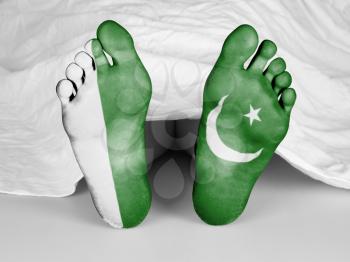 Dead body under a white sheet, flag of Pakistan