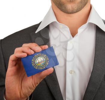 Businessman is holding a business card, flag of New Hampshire