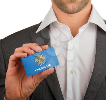Businessman is holding a business card, flag of Oklahoma