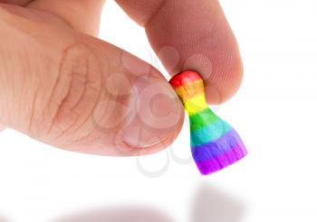 Hand holding wooden pawn with a flag painting, selective focus, rainbow flag