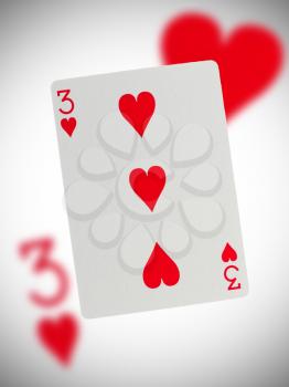 Playing card with a blurry background, three of hearts