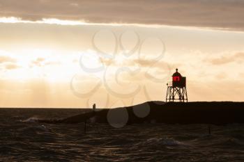 Silhouette of a red beacon at the dutch coast, sunset