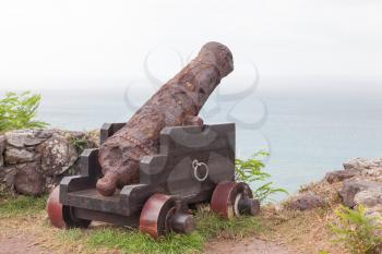 Very old rusted canon pointing at a bay, Caribbean