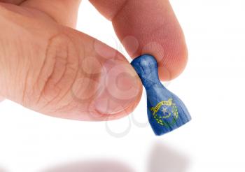 Hand holding wooden pawn with a flag painting, selective focus, Nevada