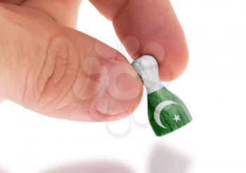 Hand holding wooden pawn with a flag painting, selective focus, Pakistan