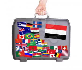 Used plastic suitcase with lots of small stickers, large sticker of Yemen