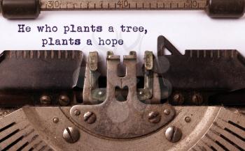 Vintage inscription made by old typewriter, he who plants a tree plants a hope
