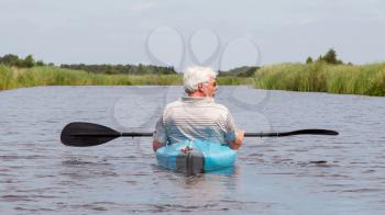 Man paddling in a blue kayak in the Netherlands