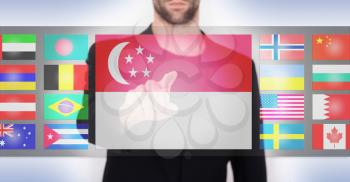 Hand pushing on a touch screen interface, choosing language or country, Singapore