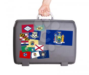 Used plastic suitcase with stains and scratches, stickers of US States, New York