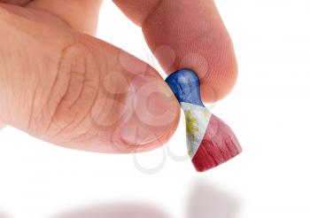 Hand holding wooden pawn with a flag painting, selective focus, Philippines