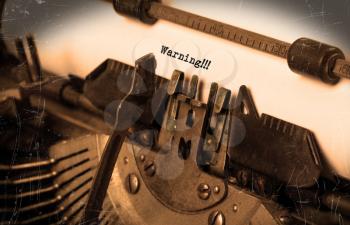 Close-up of an old typewriter with paper, selective focus, warning