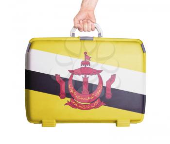 Used plastic suitcase with stains and scratches, printed with flag, Brunei