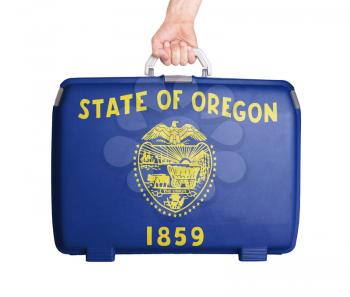 Used plastic suitcase with stains and scratches, printed with flag, Oregon