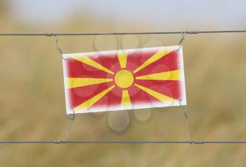 Border fence - Old plastic sign with a flag - Macedonia