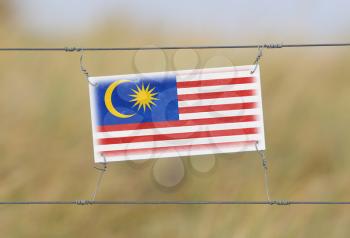 Border fence - Old plastic sign with a flag - Malaysia
