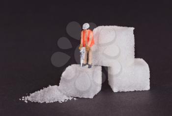 Miniature worker with drill working on a sugar cube