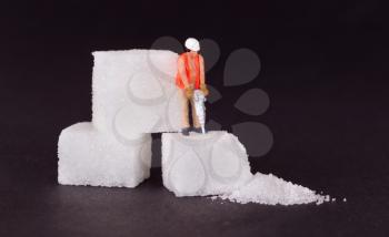 Miniature worker with drill working on a sugar cube