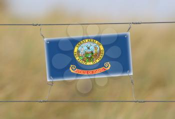 Border fence - Old plastic sign with a flag - Idaho
