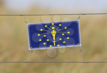 Border fence - Old plastic sign with a flag - Indiana