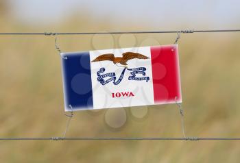 Border fence - Old plastic sign with a flag - Iowa
