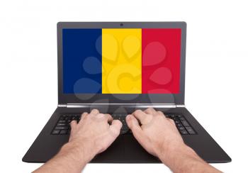 Hands working on laptop showing on the screen the flag of Romania