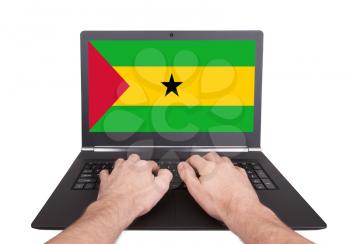Hands working on laptop showing on the screen the flag of Sao Tome and Principe