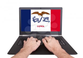 Hands working on laptop showing on the screen the flag of Iowa
